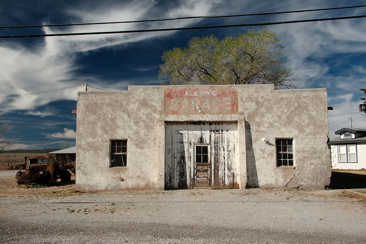 Allen’s Garage, un edificio de estuco claro con un letrero pintado en rojo desvaído y puertas de madera desgastadas, junto a un viejo camión oxidado