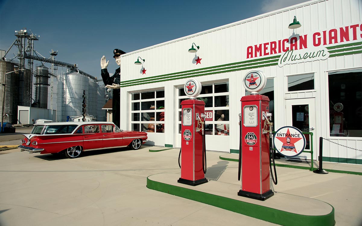El American Giants Museum en Atlanta, Illinois, con surtidores de gasolina rojos y un auto clásico delante