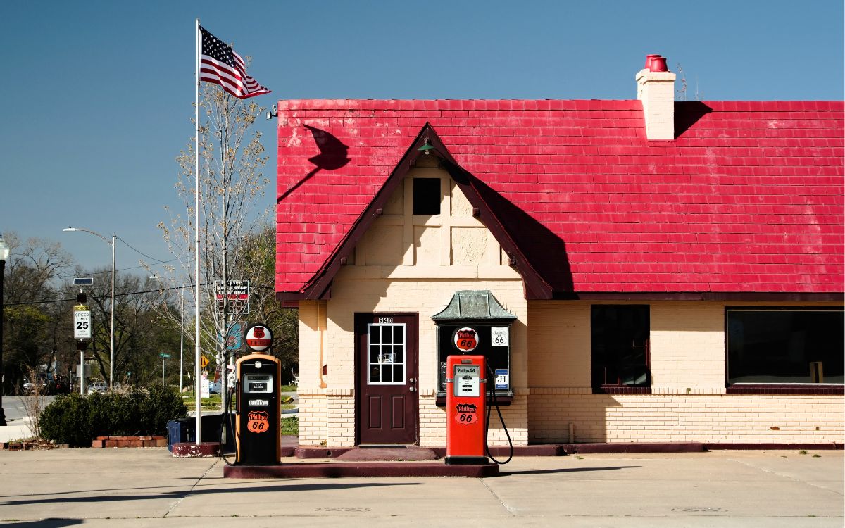 Una gasolinera de ladrillo color crema, estilo cabaña, con techo rojo empinado y dos bombas rojas de Phillips 66