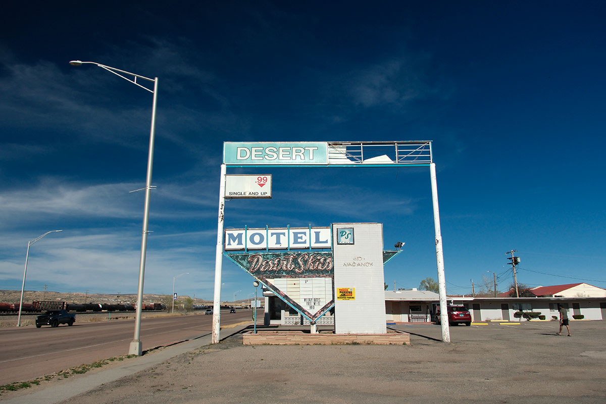 El letrero del Desert Skies Motel en Gallup, con el panel superior medio vacío, sobre la oficina cerrada del motel
