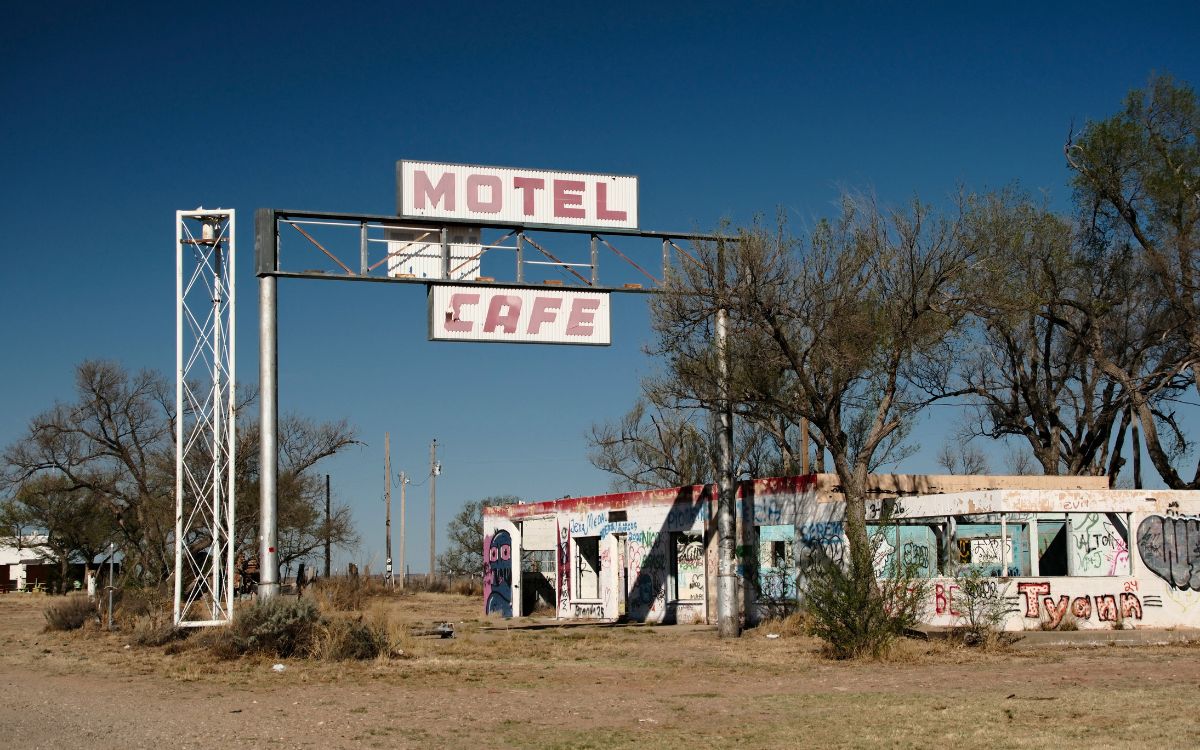 Las ruinas cubiertas de grafitis del Texas Longhorn Motel and Café en Glenrio, bajo un marco de letrero Motel Cafe vacío