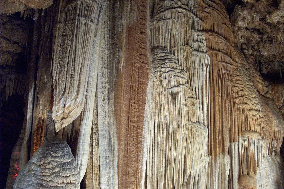 Formaciones de flujo de calcita en tonos crema y óxido dentro de Meramec Caverns