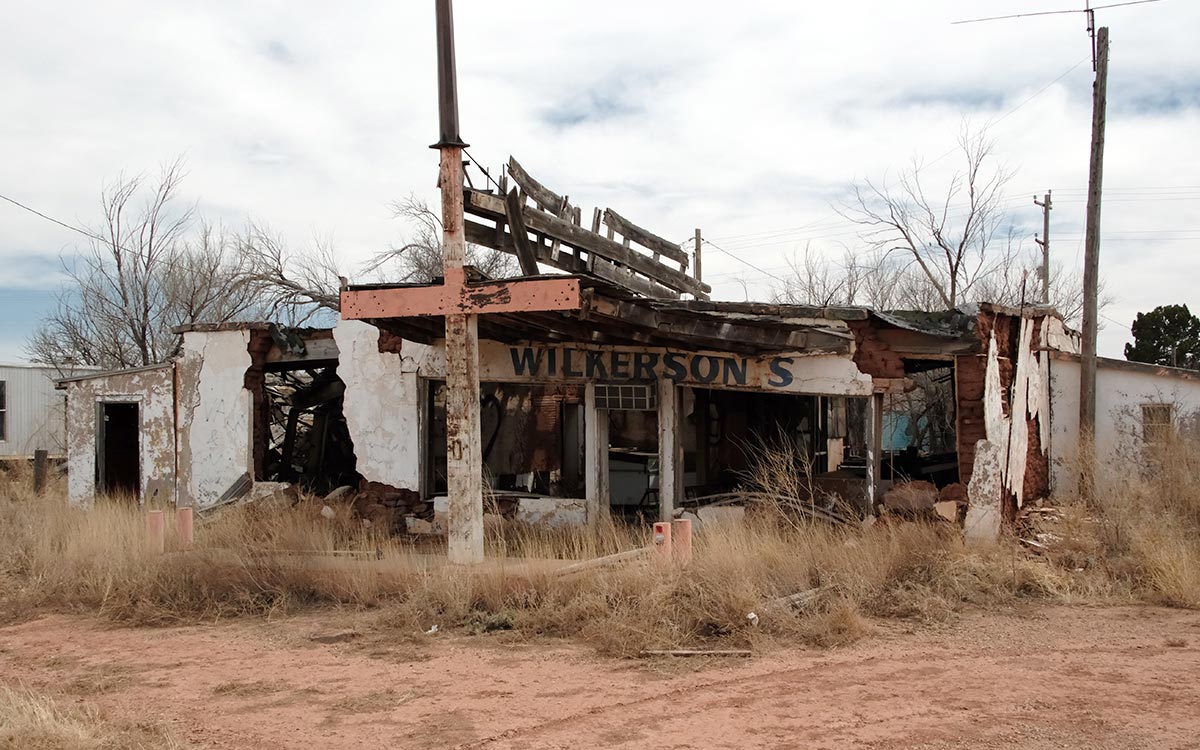 La carcasa de adobe a punto de derrumbarse del Wilkerson’s Country Store and Gulf station entre hierba seca