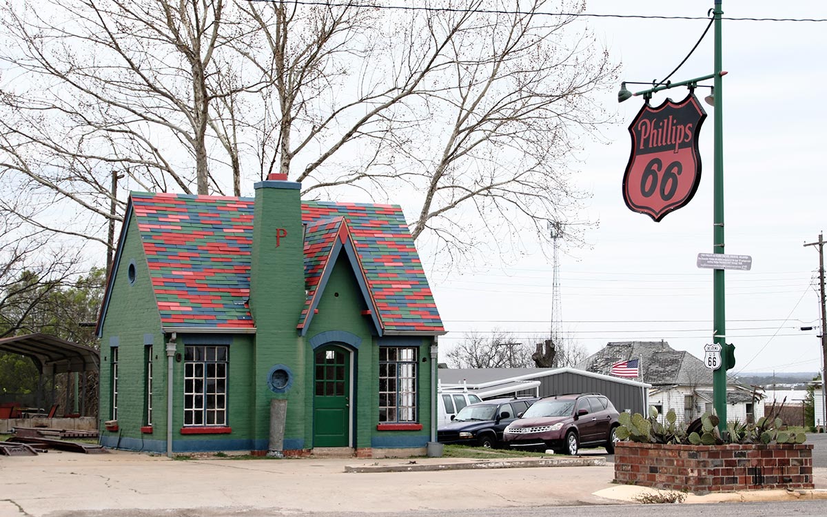 Une petite station Phillips 66 verte de style cottage, avec un toit à motifs et une enseigne Phillips 66