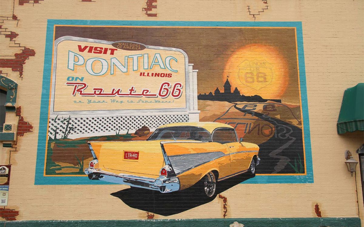Un mural pintado de Visit Pontiac, Illinois, on Route 66 con un Chevrolet 1957 amarillo