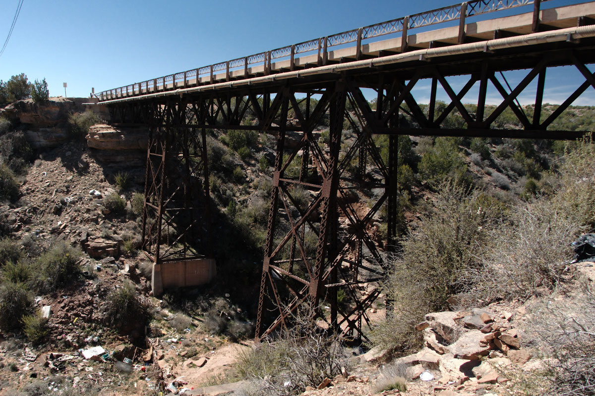 Un puente de acero de armadura de tablero superior que lleva el camino viejo muy en lo alto sobre un cañón rocoso del desierto