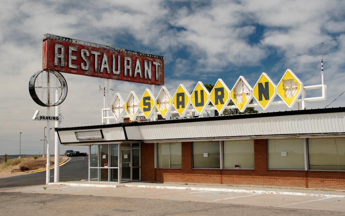 El Route 66 Restaurant cerrado en Santa Rosa, con su oxidado letrero Restaurant formado por paneles amarillos en forma de rombo, varios de ellos ausentes, contra un cielo nublado