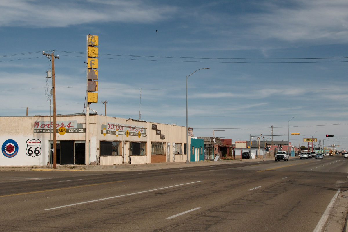 El salón de exhibición vacío de Dickinson Motors en la Route 66 de Tucumcari, bajo un letrero amarillo desvaído que dice Café