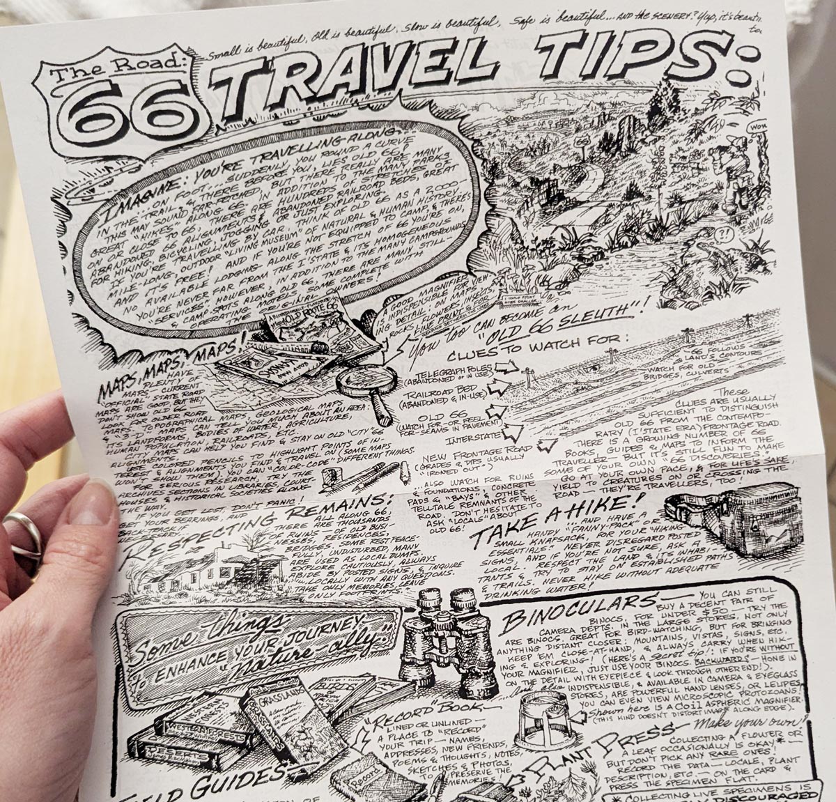 Una mano sostiene la hoja «Route 66 Travel Tips» dibujada a mano por Bob Waldmire, llena de ilustraciones y notas